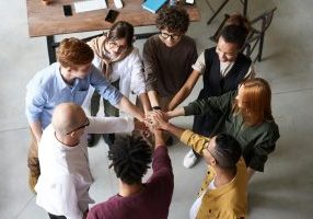Diverse group stacking hands in center.
